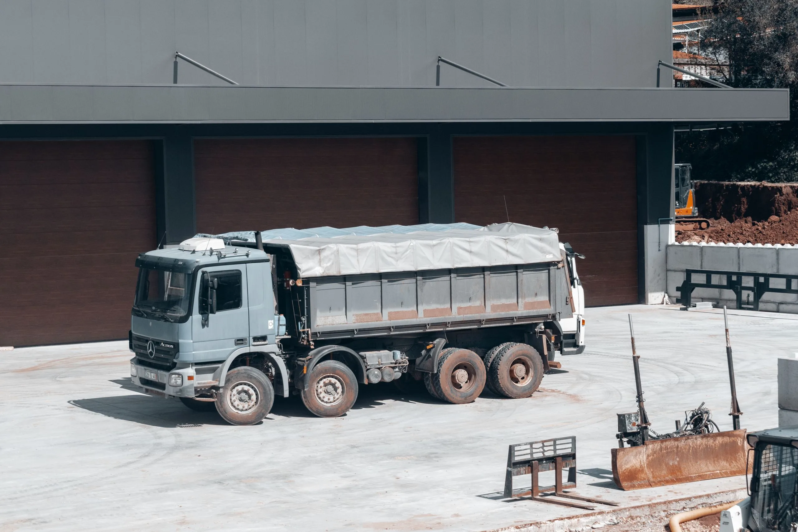 Camion benne de location chargé de gravats devant une maison en travaux